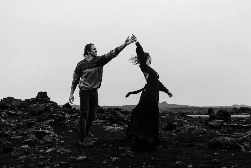 A black and white image of a young couple dancing in the rain.