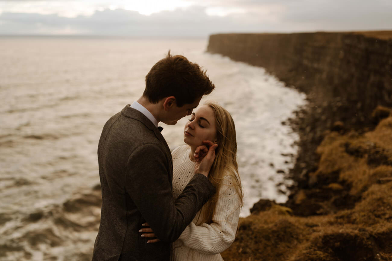 A cinematic frame of a couple standing on cliff in fall light