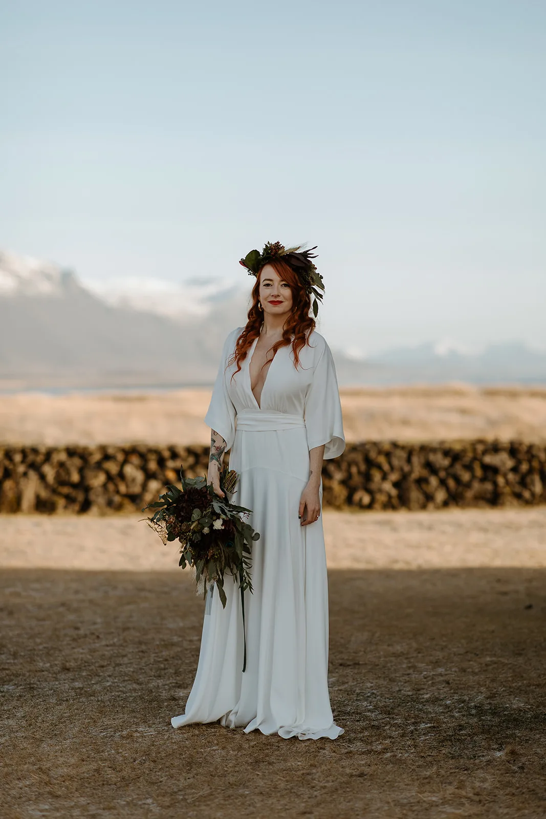 Redheaded bride posing with a wild flower bouquet and a flower crown