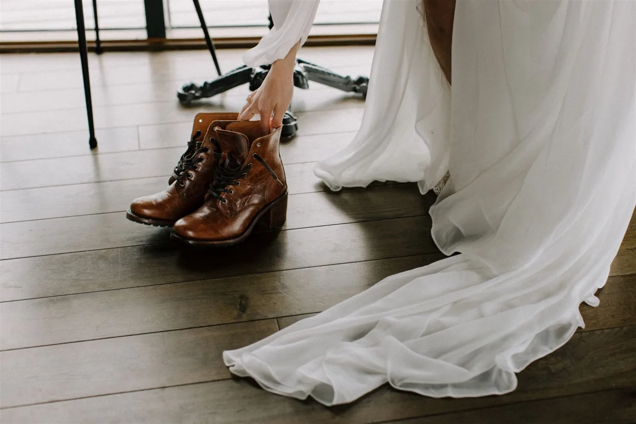 Good boots are important for an Iceland Elopement, bride reaching for her boots.