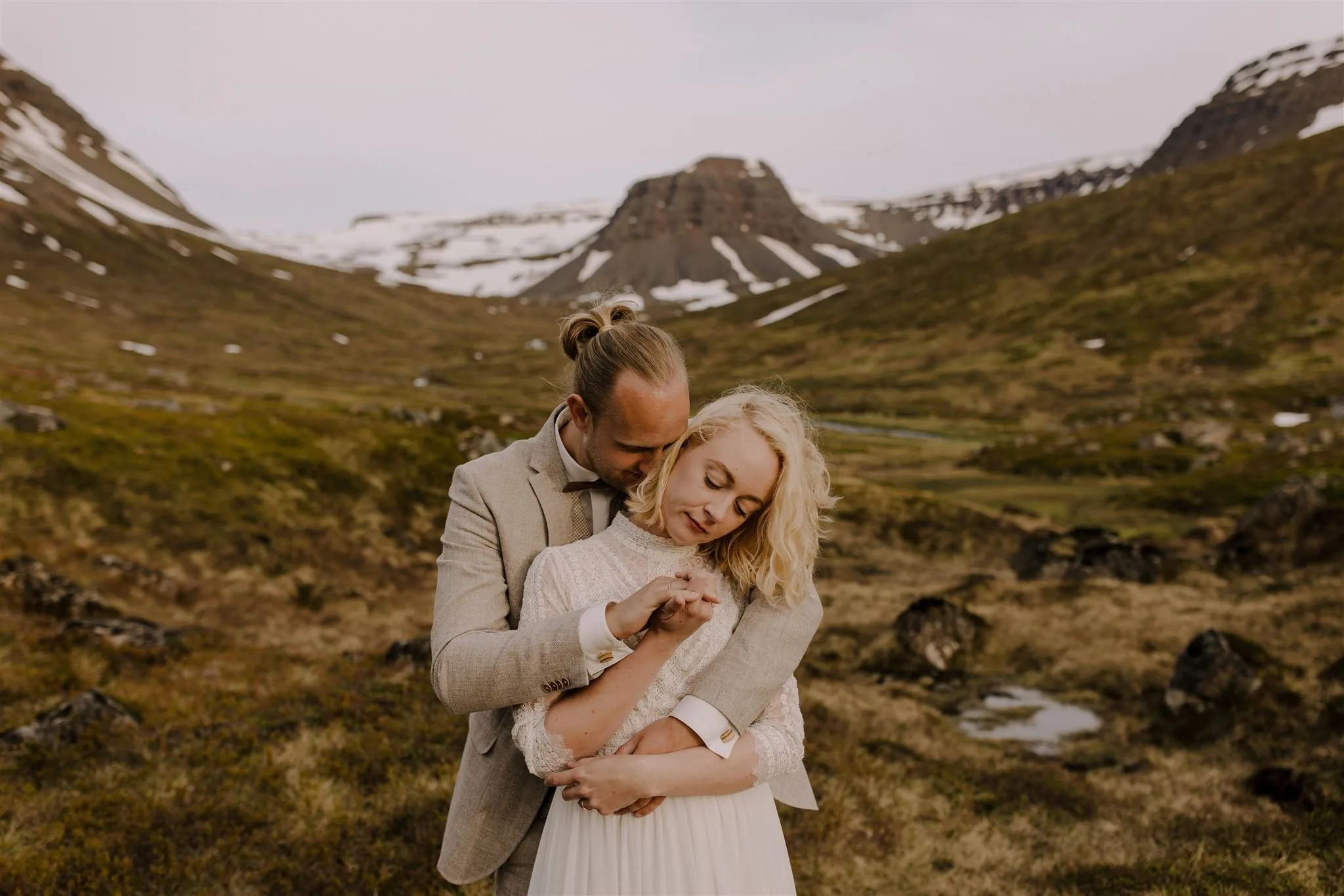 A bride and groom in a warm embrace at the edge of the world in the Westfjords of Iceland during their Iceland elopement.