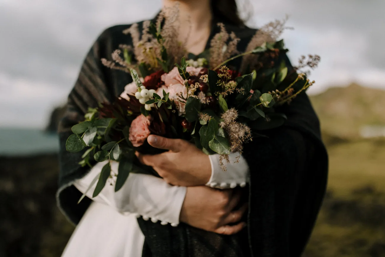 Bride holding a wild bouquet of flowers in her arms.