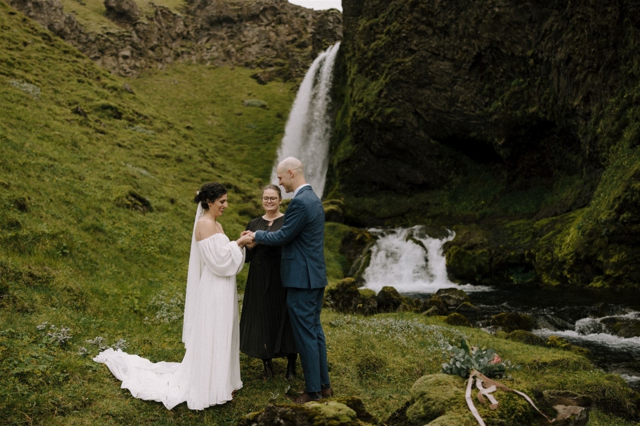 Exchanging rings in front of a waterfall during an Iceland elopement ceremony.