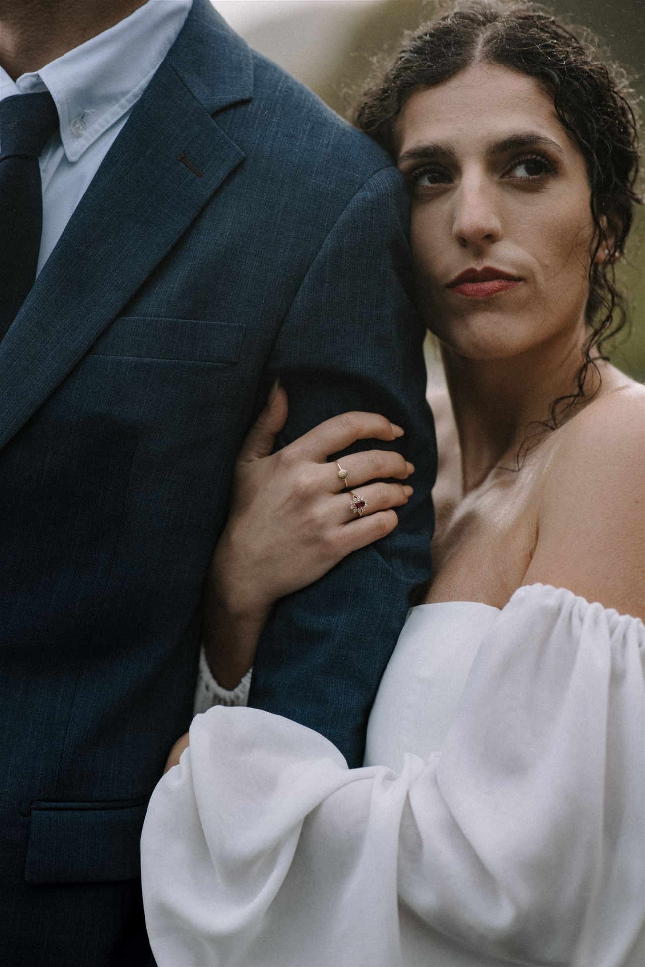 A close up of a bride clutching her husbands arm as they gaze through the waterfall mist on the south coast during their Iceland elopement.