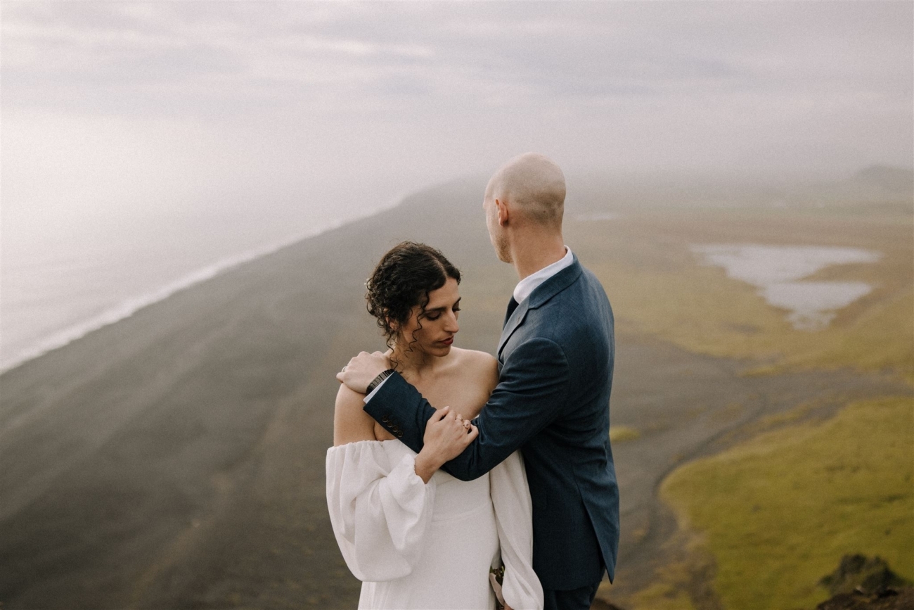 A soft embrace with the endless black sands stretching out behind a bride and groom during their Iceland elopement.
