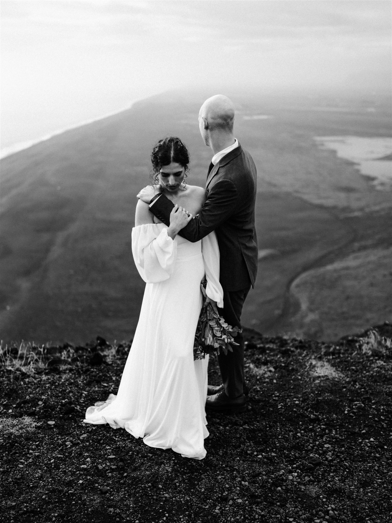 A soft embrace with the endless black sands stretching out behind a bride and groom during their Iceland elopement.