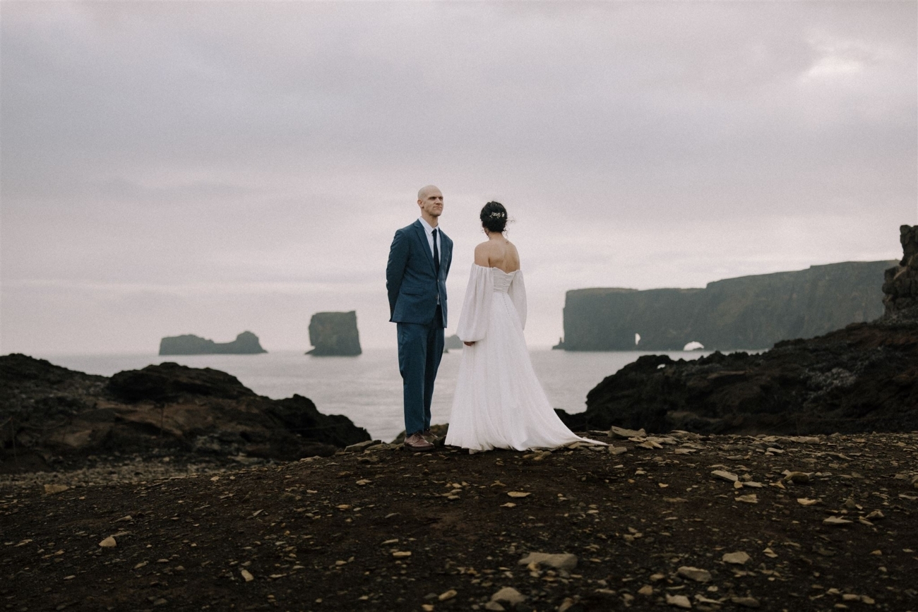 A bride and groom adventuring among the sea cliffs of the south coast of Iceland on their elopement day.