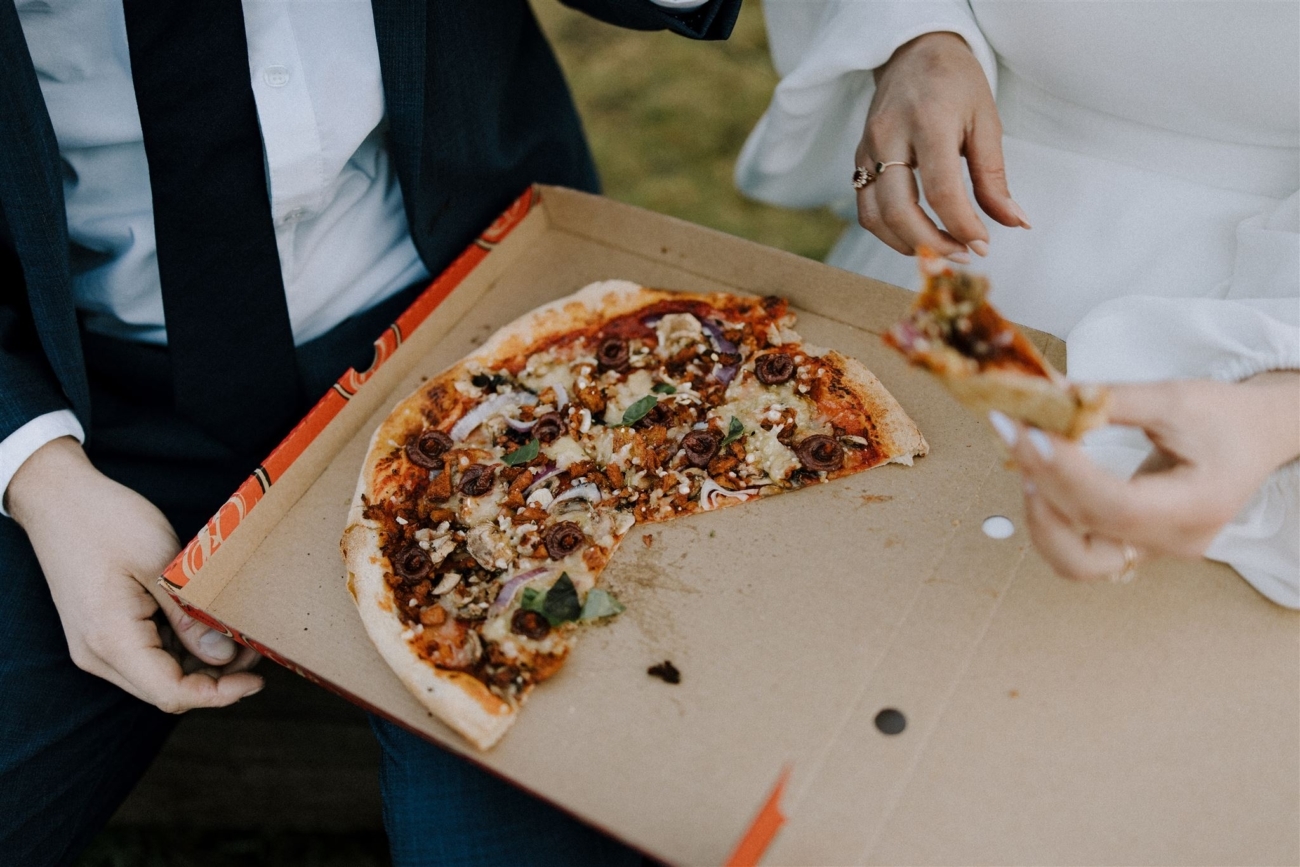 A bride and groom enjoy a pizza instead of a fancy dinner on their elopement day in Iceland.