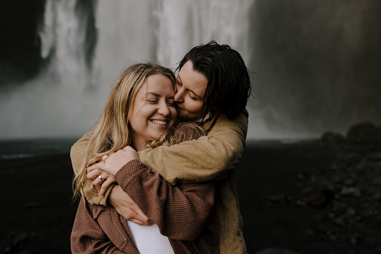A tight hug in front of the roaring waterfall.