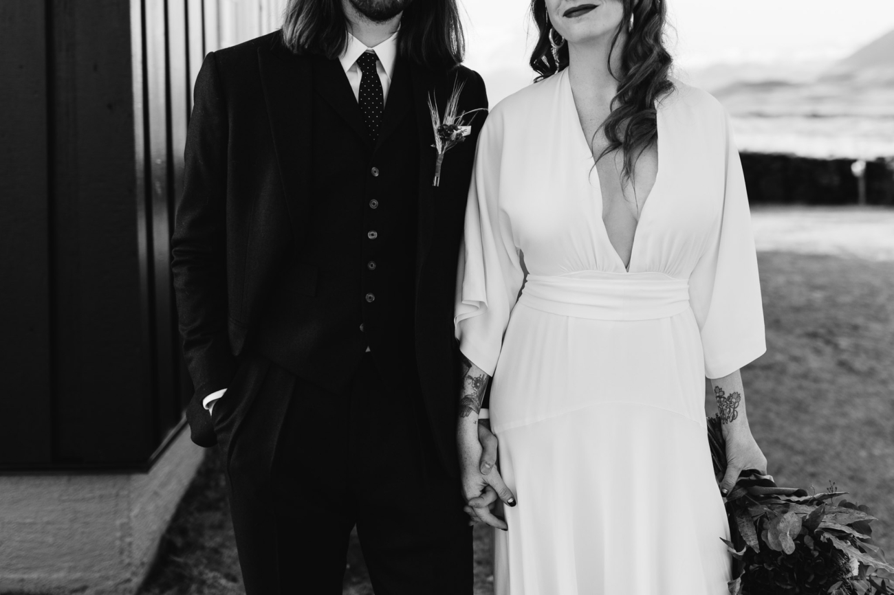 Stylish wedding couple poses outside the black church in west Iceland.