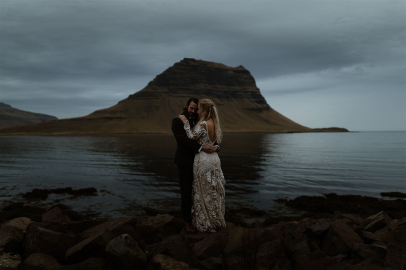 A couple in a warm embrace at dusk in front of the Kirkjufell mountain in Iceland.