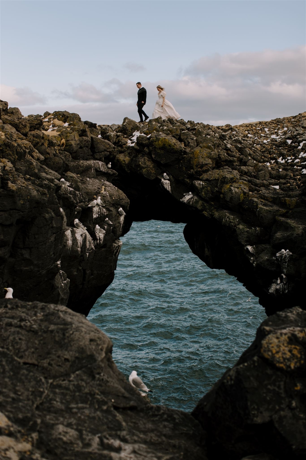 A couple walking across a stone bridge.