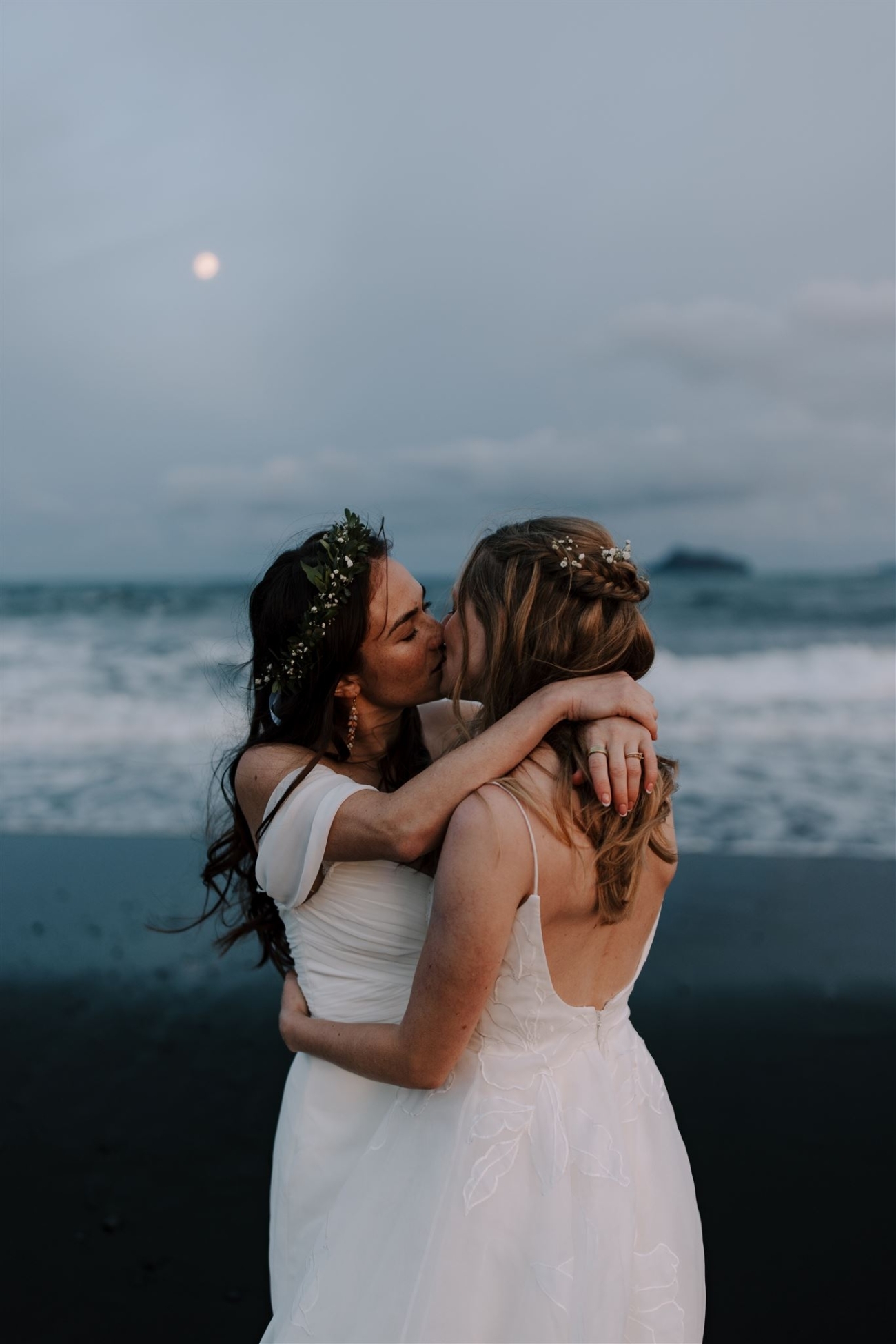 A lesbian couple kissing in the moon light.