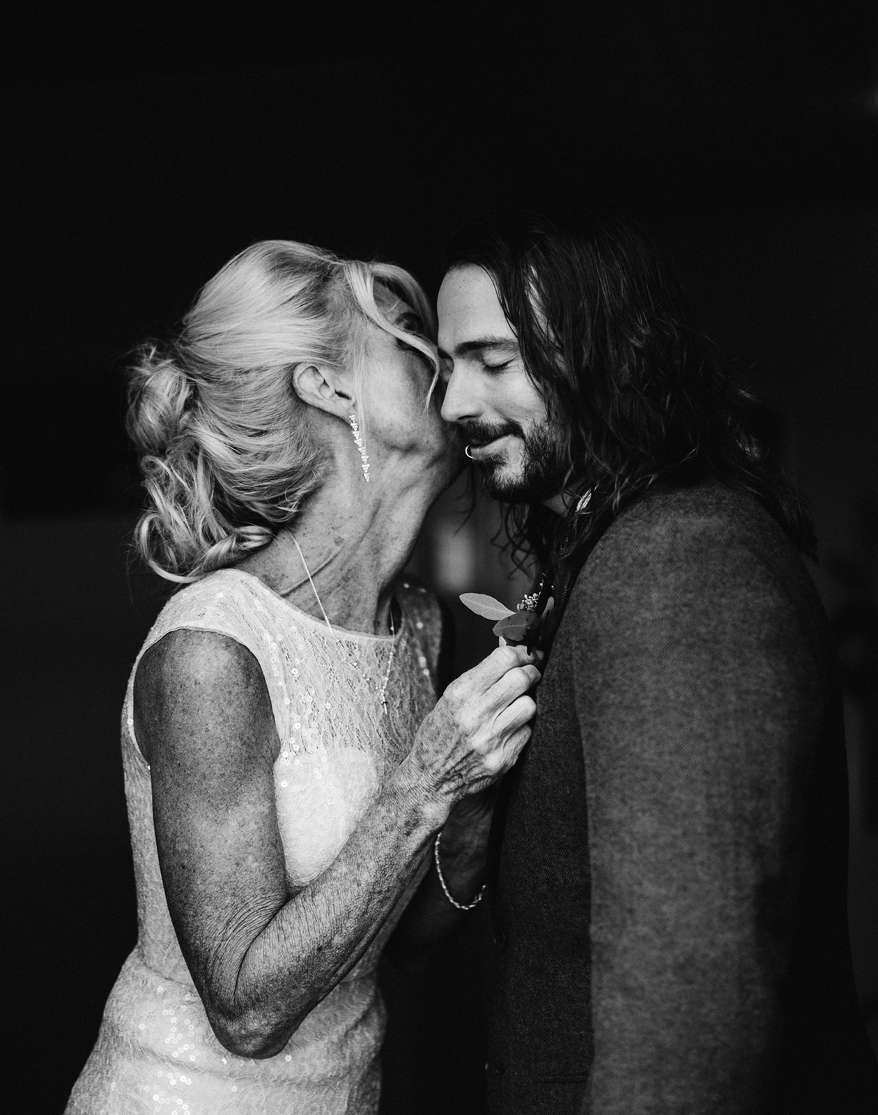 mum kissing a groom during getting ready pictures