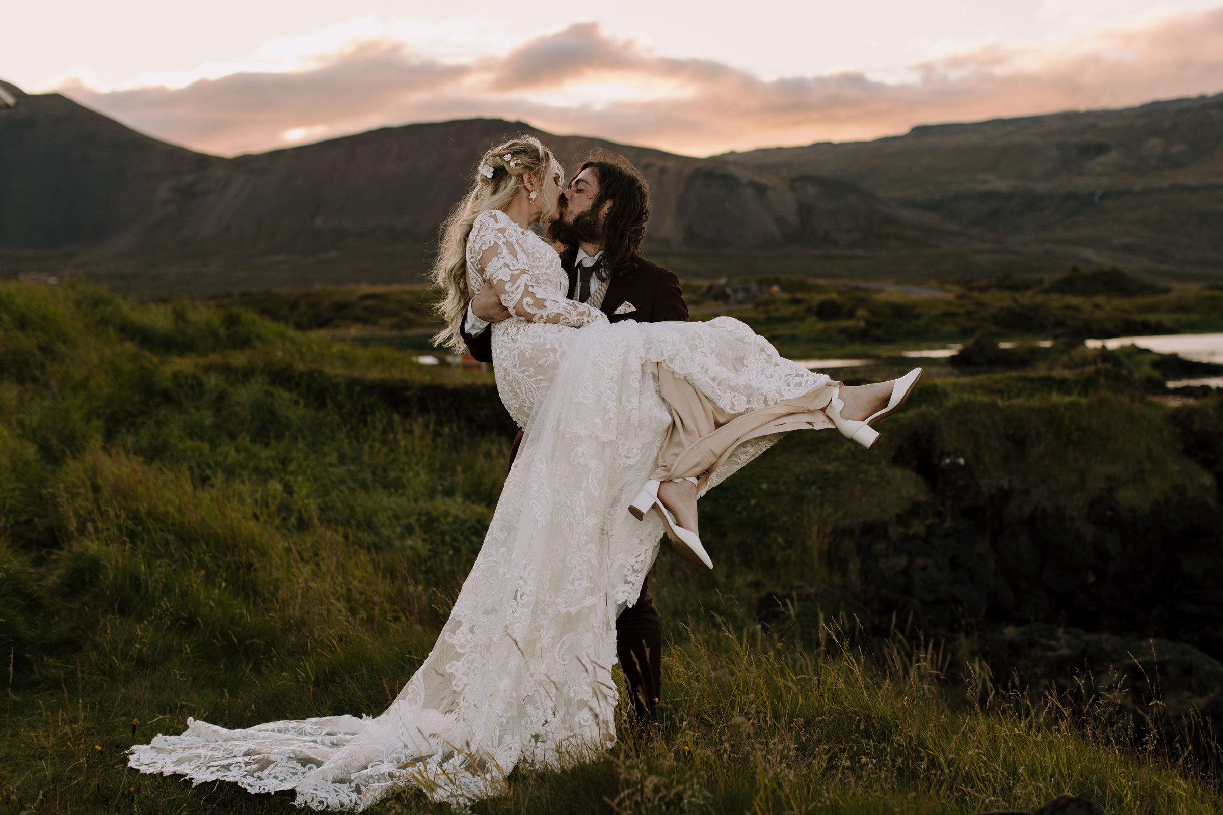 Groom holding a bride in his arms and kissing her.