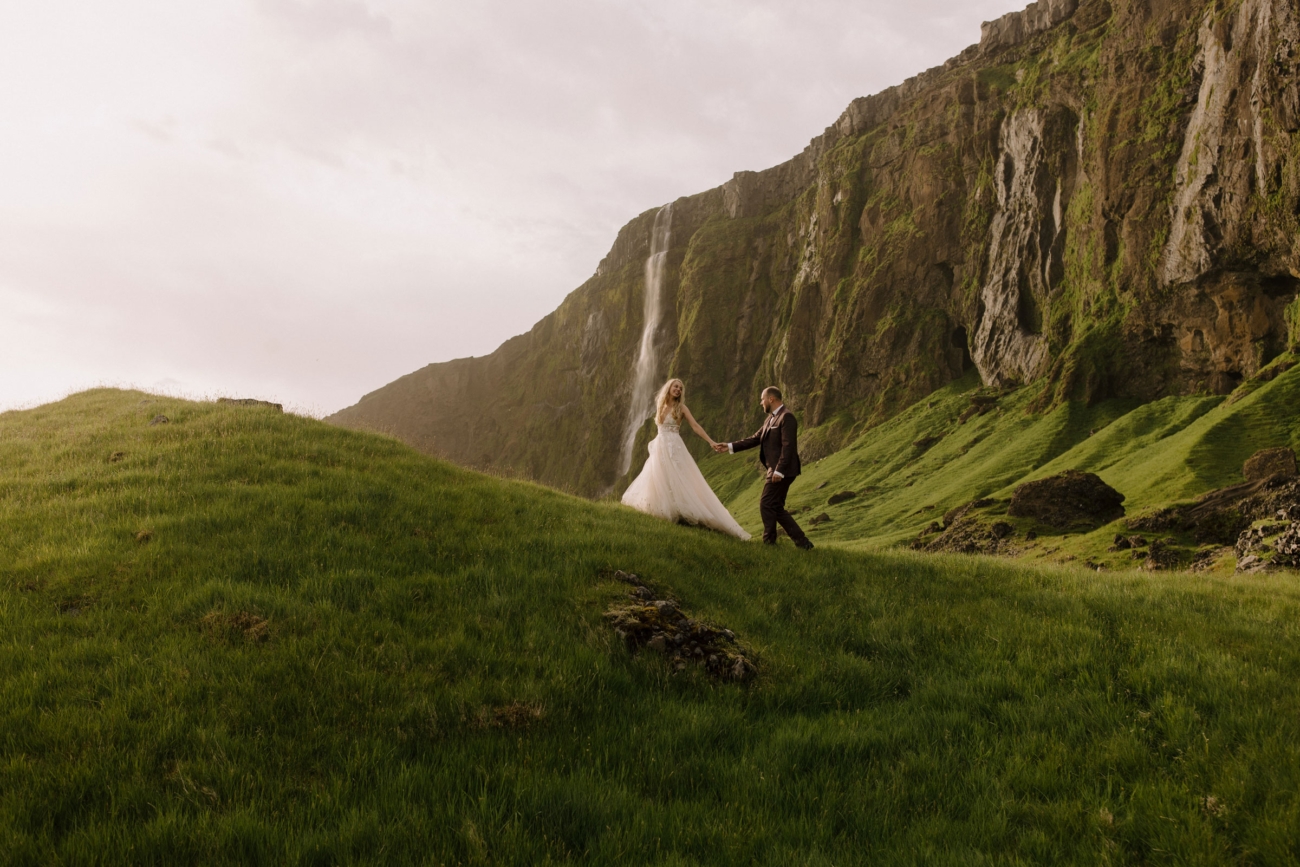A couple hiking in lush green landscapes during the midnight sun in Iceland.