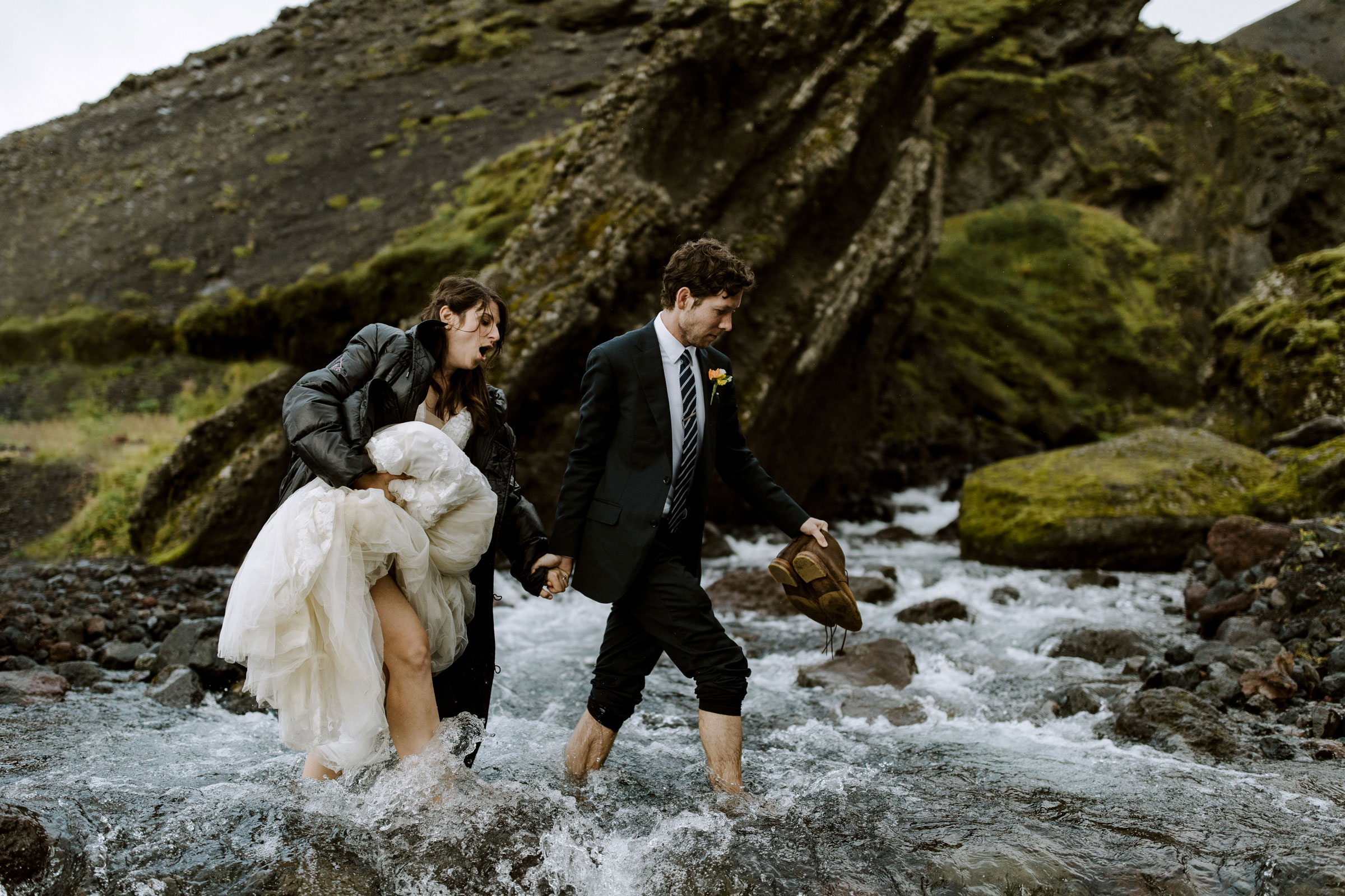 Bride and groom cross a stream on foot during and adventure wedding in Iceland