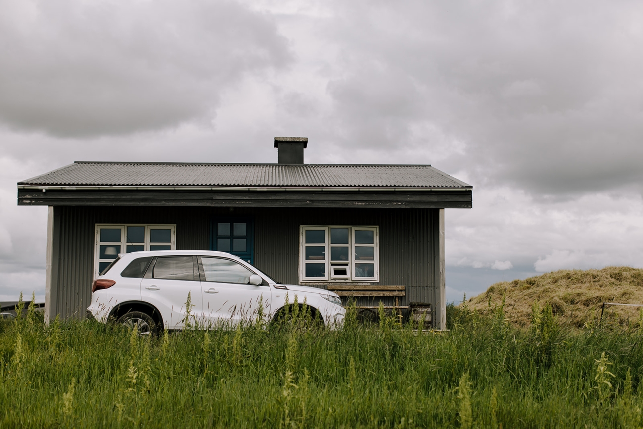 A rental car parked out side a cute cabin - available for rent in rural Iceland.