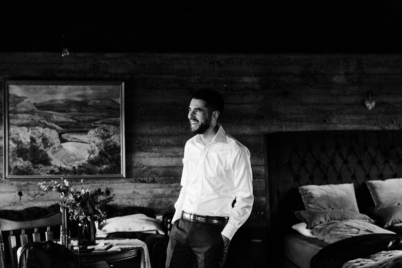 A groom looks expectantly out the window as he gets ready for his wedding day.