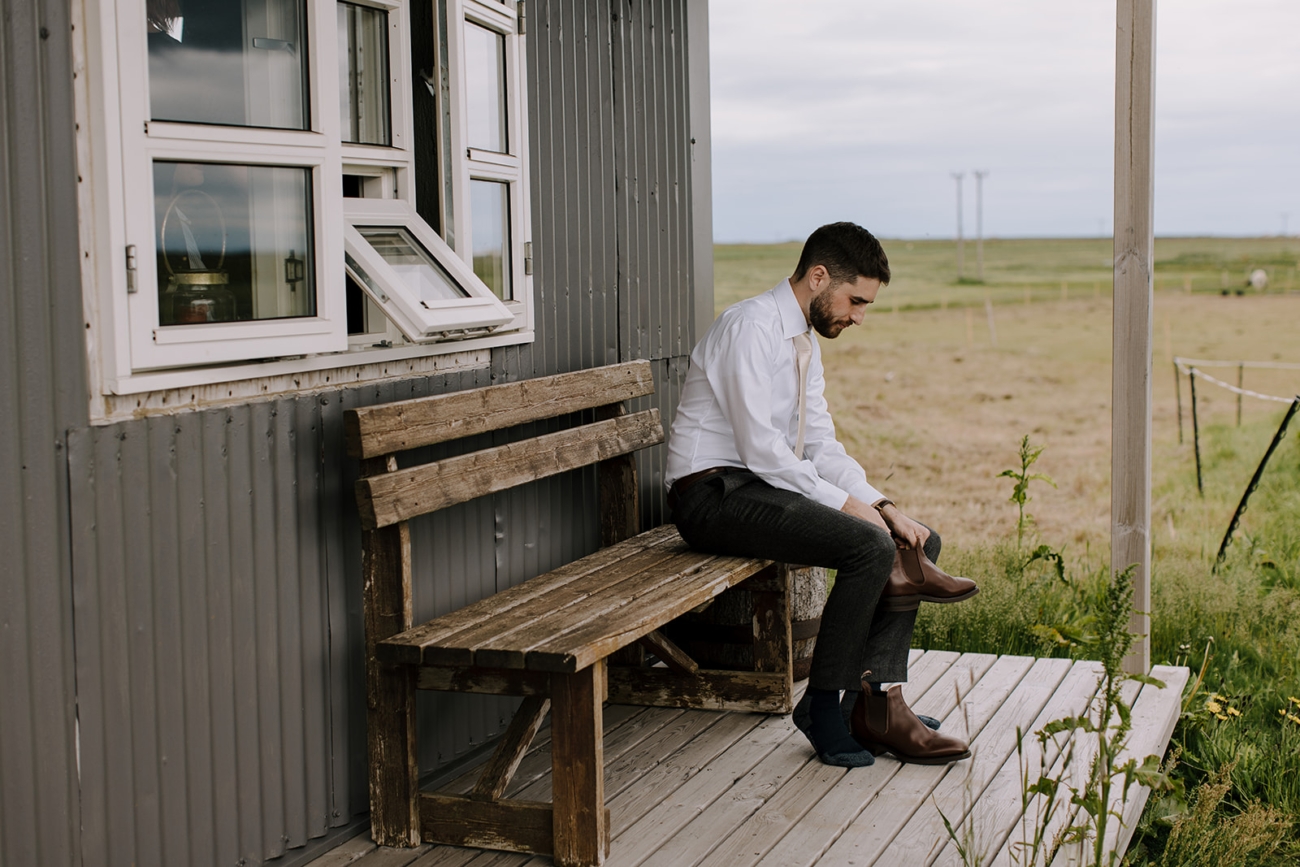 A groom puts on his shoes on the porch of his cabin before heading out for an adventurous elopement. 