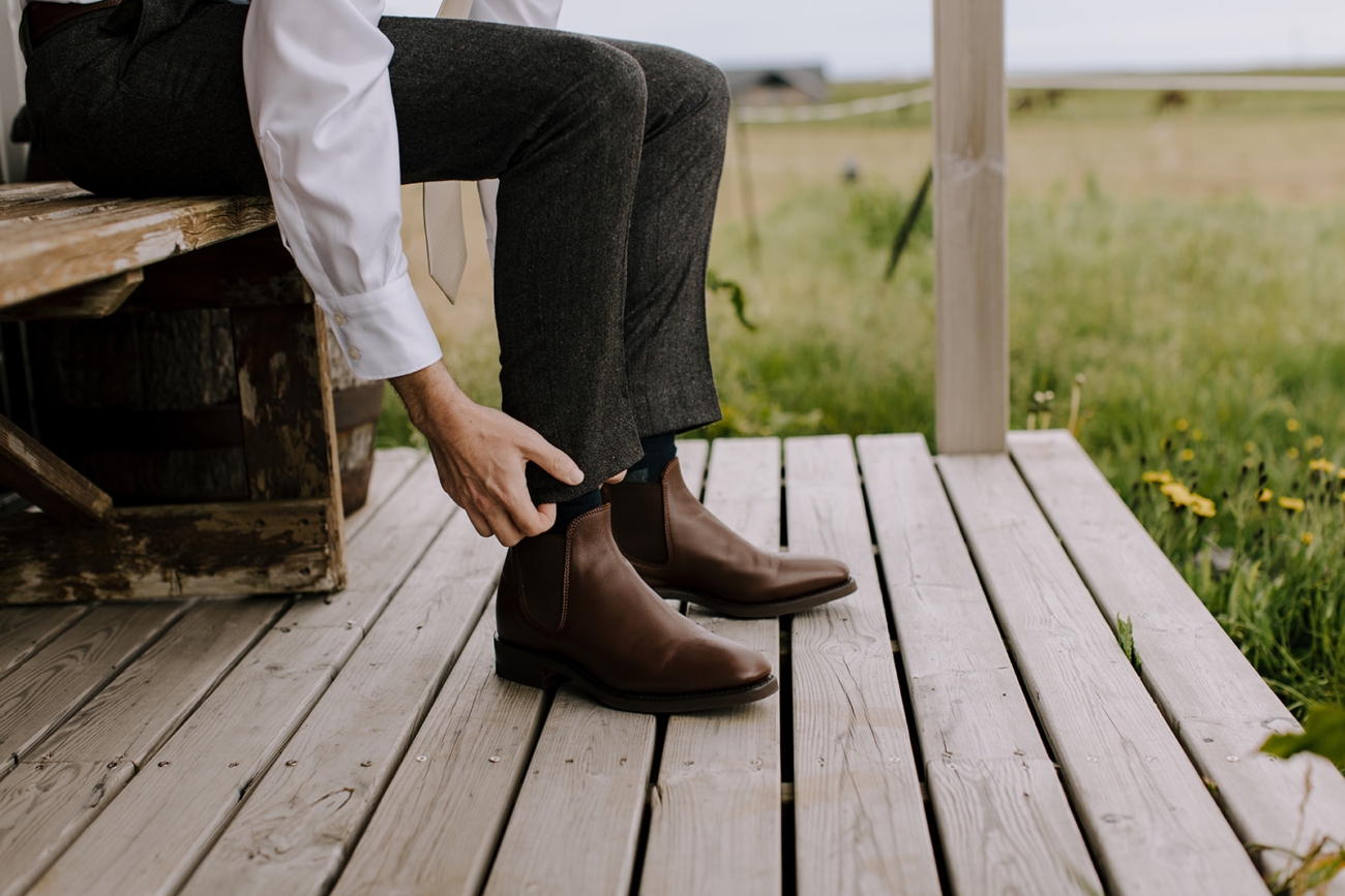 A groom puts on his shoes on the porch of his cabin before heading out for an adventurous elopement. 