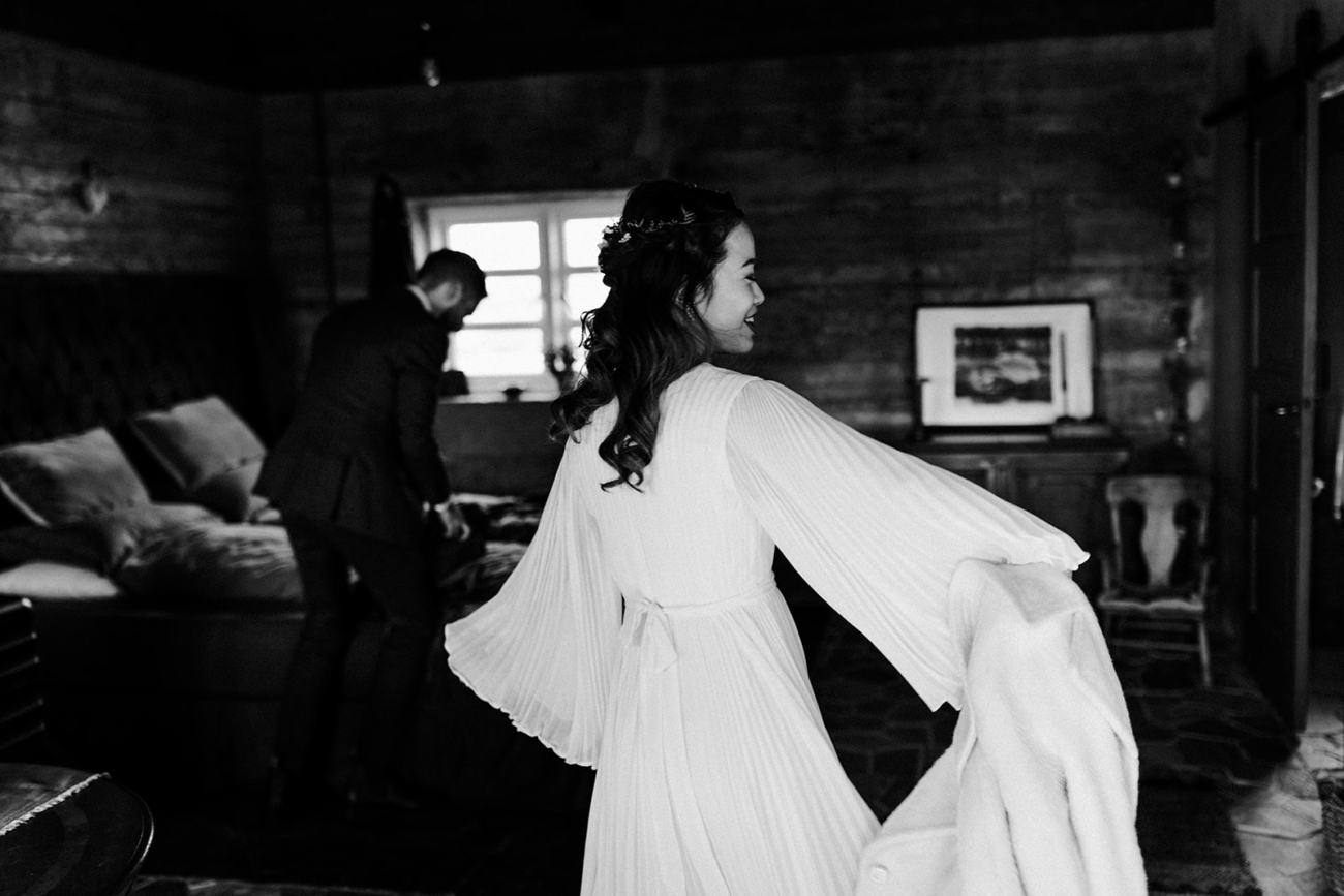 A bride twirls her dress as she finishes getting ready in a cozy cabin in the countryside.