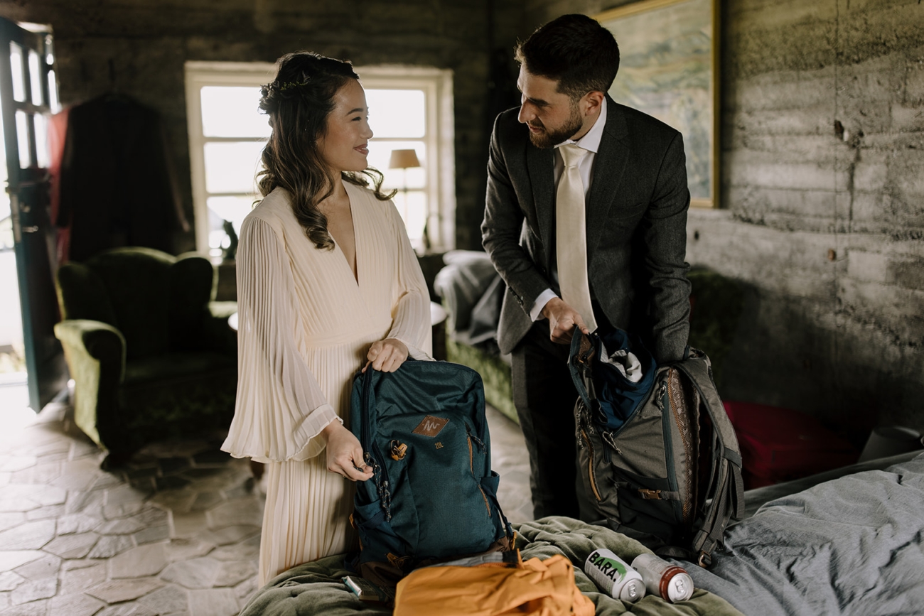 A couple packs their backpacks as they head out on a hike to their elopement ceremony. 
