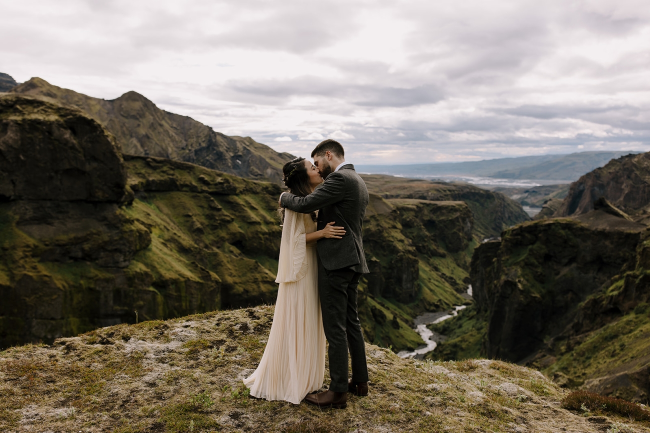 A bride and groom kissing for the first time as a married couple high up in the mountains, after their elopement ceremony. 