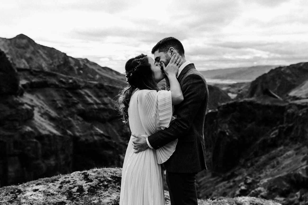 A bride and groom kissing for the first time as a married couple high up in the mountains, after their elopement ceremony. 