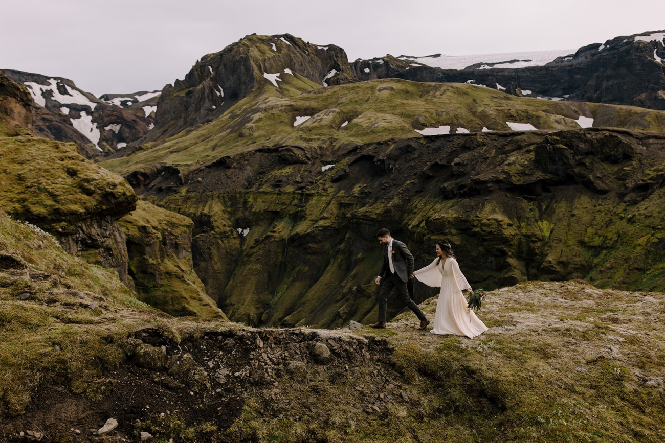 Couple walking along a mossy canyon in the mountains of Þórsmörk.