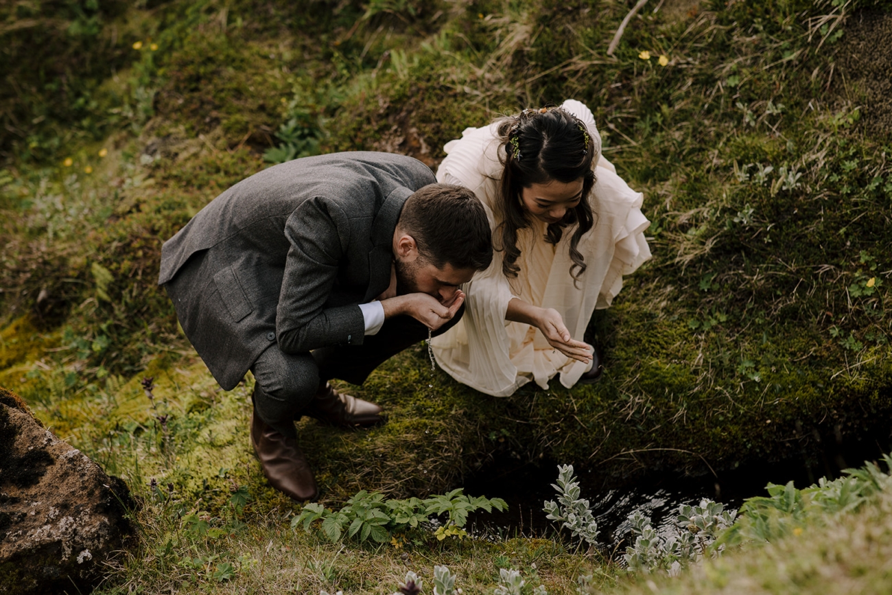 Having a drink straight from a stream during an elopement in the mountains.