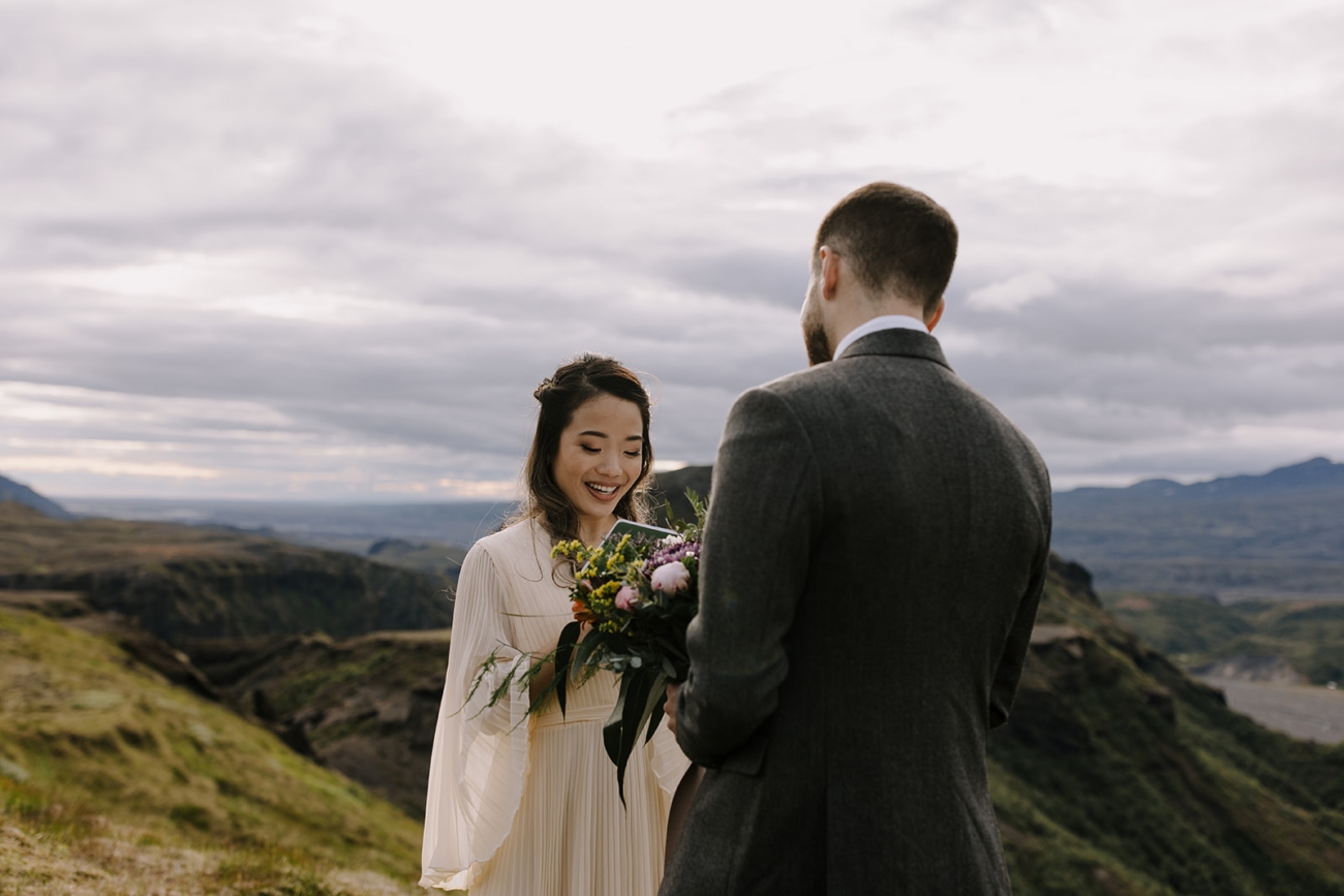 A bride smiles as she reads her personal vows for her husband.