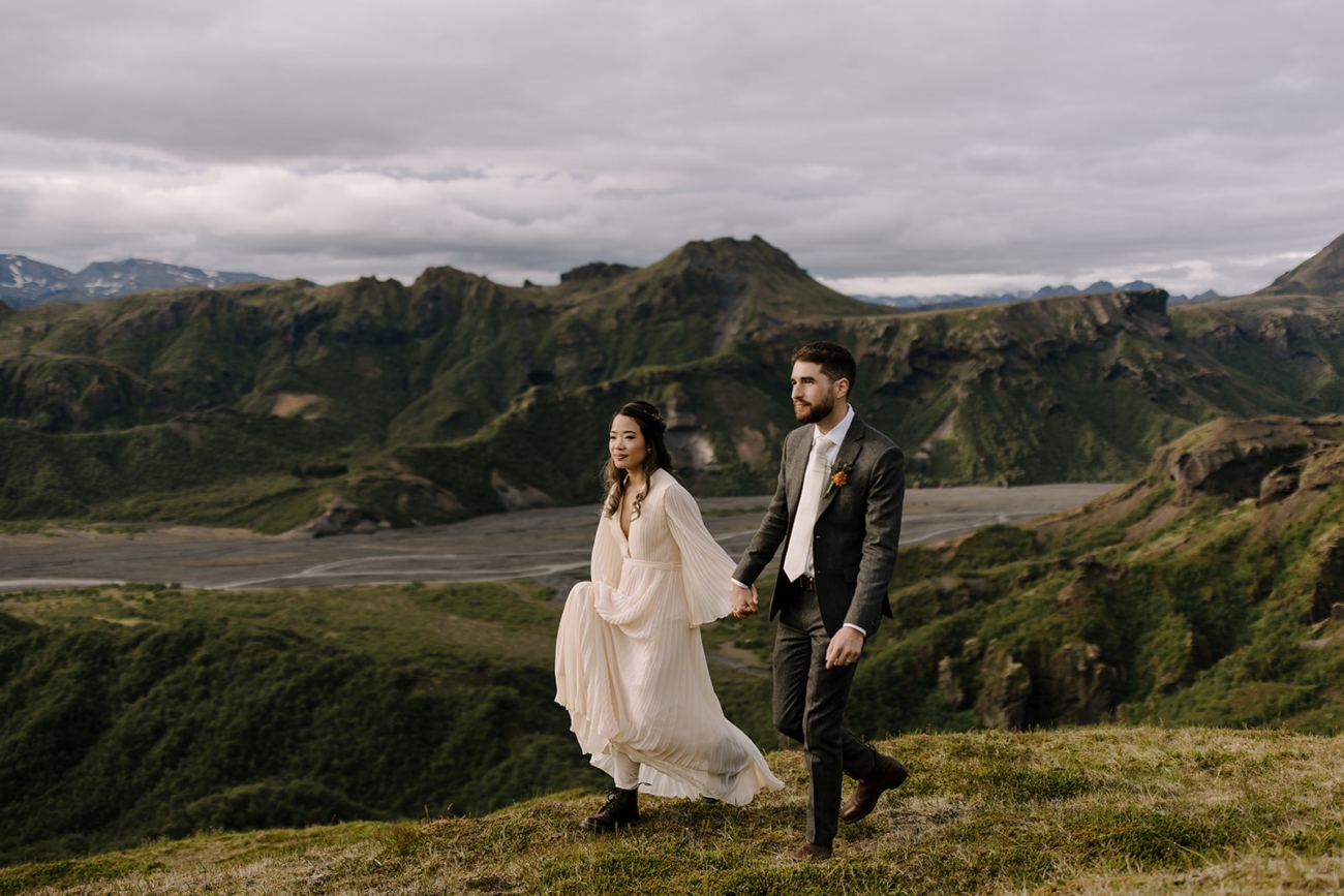 A flowy dress and a sharp suit walk along a mountain ridge in Þórsmörk.