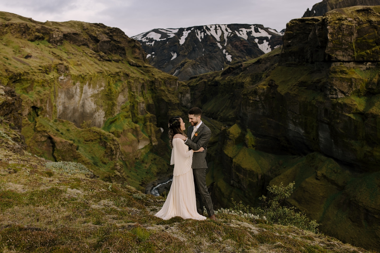 A couple posing in front of a dramatic moss covered canyon in Þórsmörk.