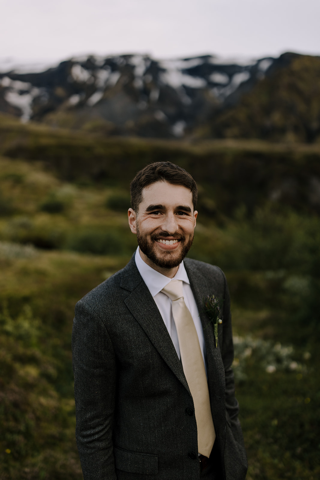 A smiling portrait of a groom in the mountains.