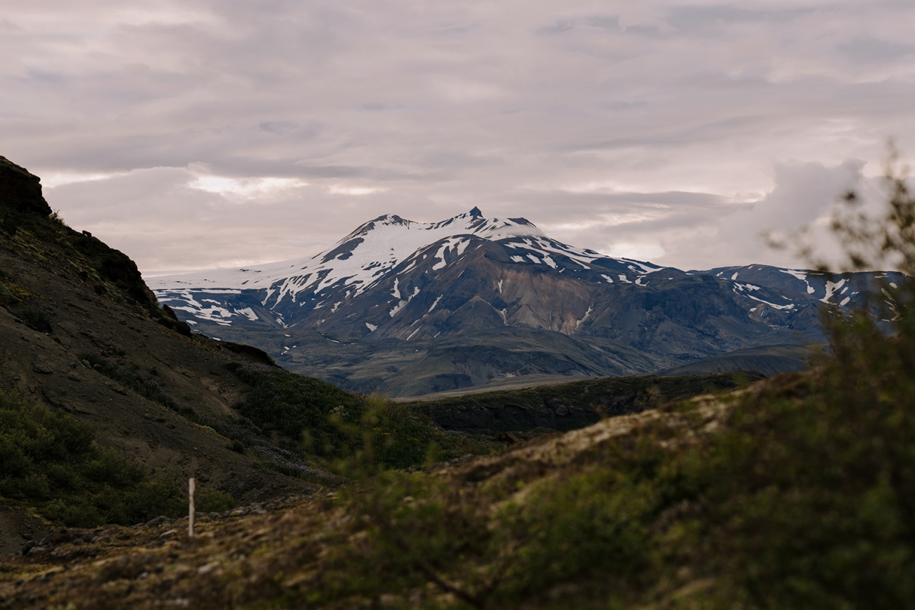 A snow caped mountain looms in the distance on a hike in Þórsmörk, Iceland.