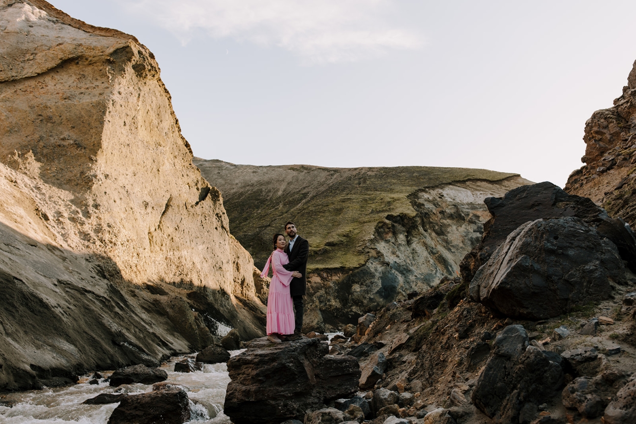 A couple standing a top a big rock gazing at the vast landscapes around them during a photoshoot in the highlands of Iceland.