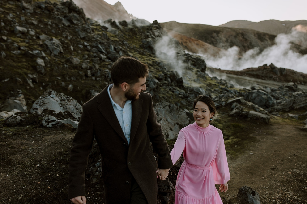 Steam still rises from an ancient lava field as a couple walks past it. 