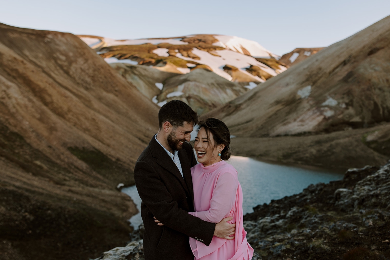 A couple bursts out laughing on a hike in the mountains on their Iceland Elopement day. 