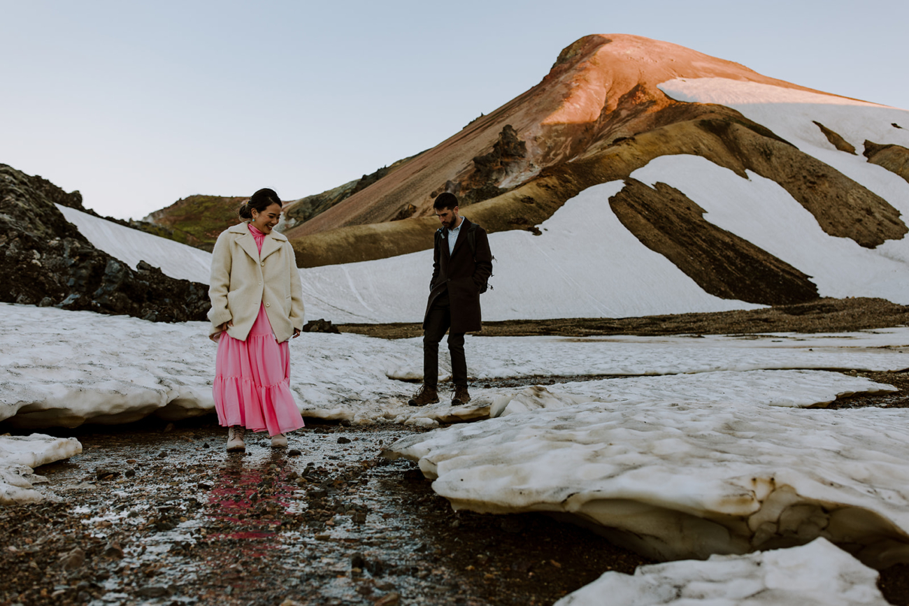 A couple traverses the snow covered walking paths of Landmannalaugar Iceland.