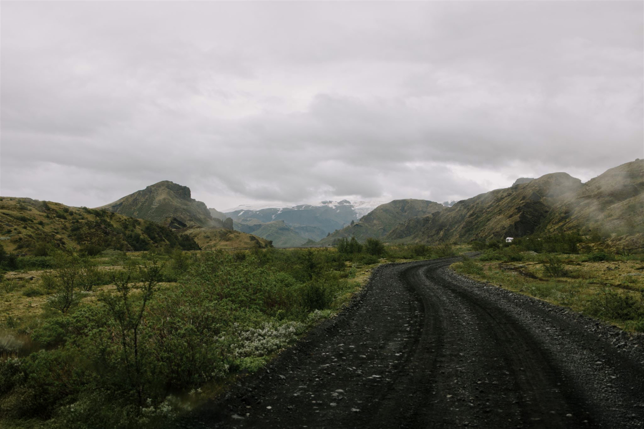 A road leading to the valley of Þórsmörk, surrounded by lush greenery. 