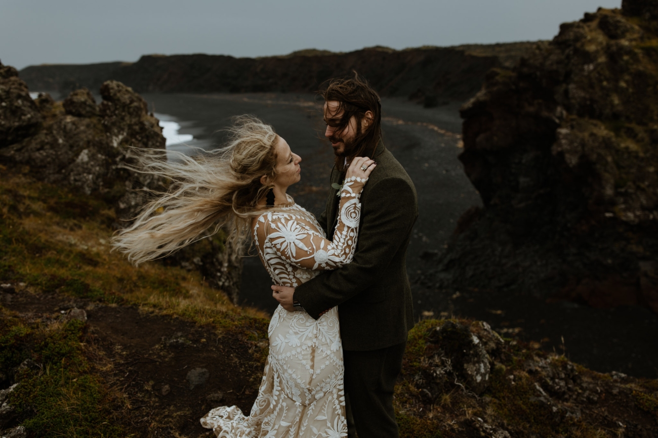 A couple embracing on a windblown cliff in Iceland on their wedding day.